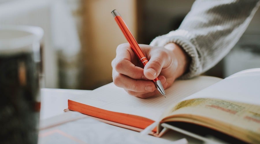 Person writing in a notebook with a pen