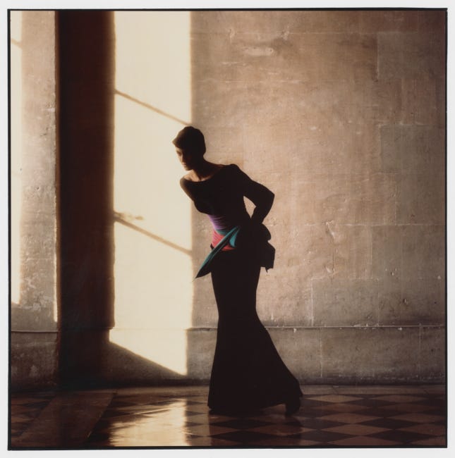 Jeune femme dans une robe de cocktail de luxe, photographiée à contre-jour dans un intérieur ancien.