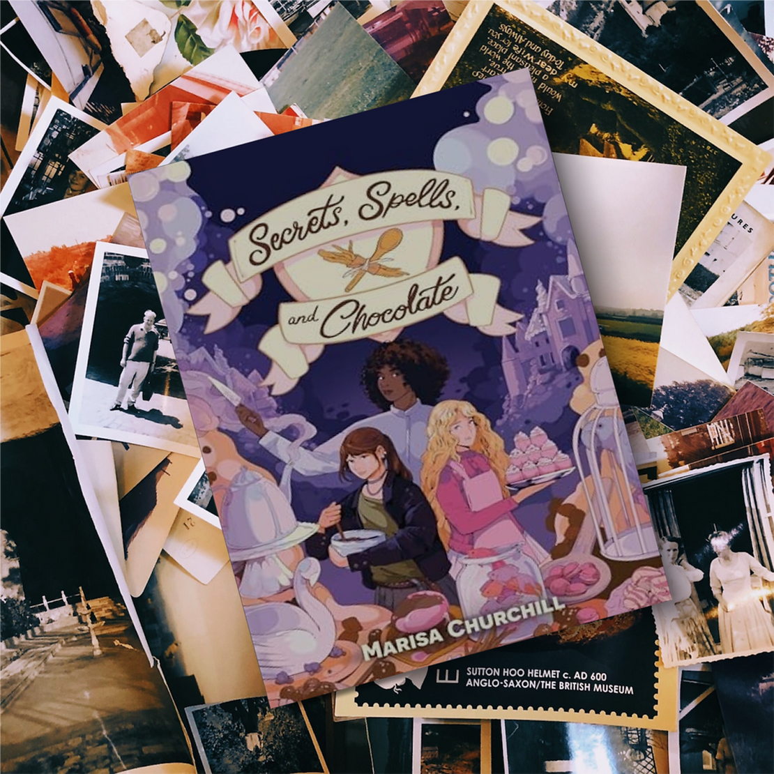 Book "Secrets, Spells, and Chocolate" by Marisa Churchill on top of photos and magazines Book "Secrets, Spells, and Chocolate" by Marisa Churchill on top of photos and magazines
