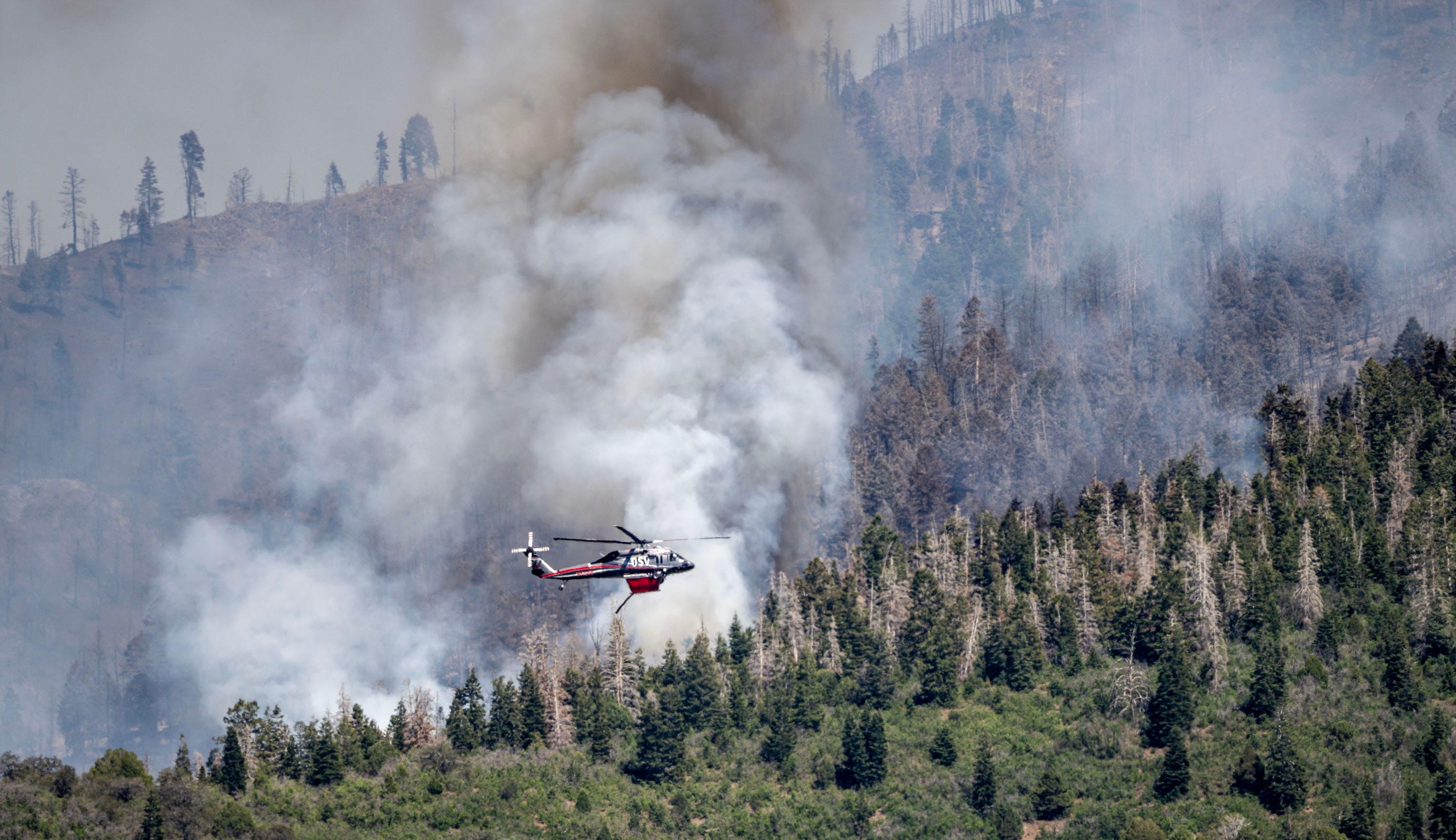 A helicopter drops fire retardant on a Utah mountain.