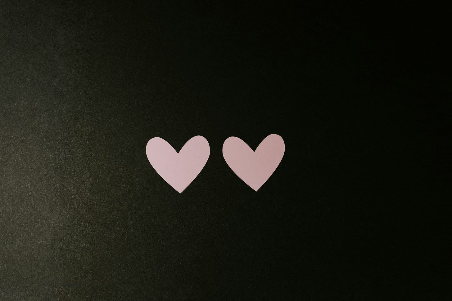 Two paper hearts on a black surface Two paper hearts on a black surface