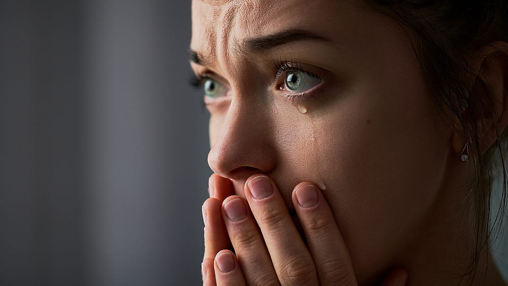 Photo of crying woman with her hands held up to her face and her eyes open wide as if looking at something she can’t believe she is seeing. Photo of crying woman with her hands held up to her face and her eyes open wide as if looking at something she can’t believe she is seeing.