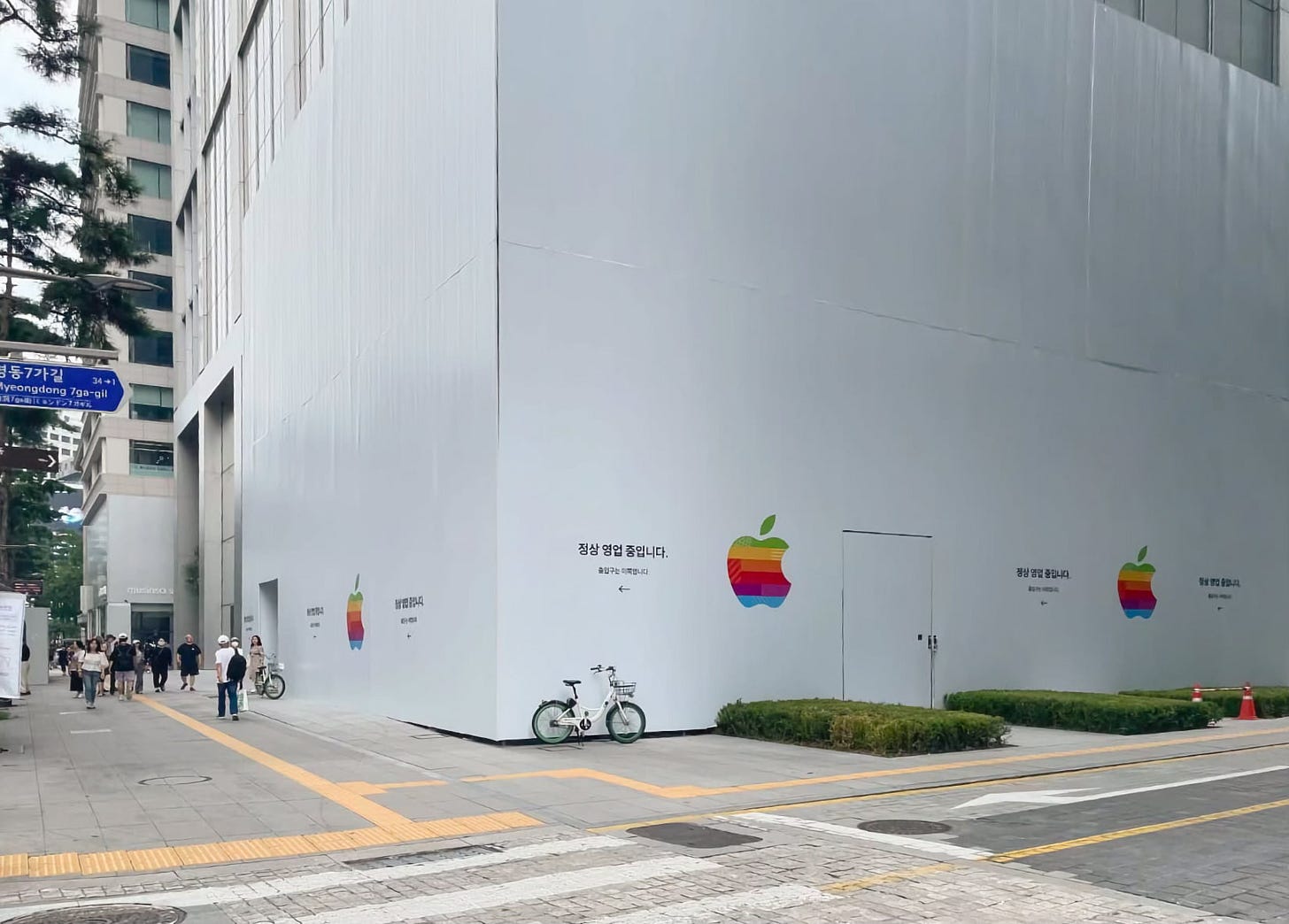 A large white barricade with an Apple logo surrounds part of the exterior facade at Apple Myeongdong. A large white barricade with an Apple logo surrounds part of the exterior facade at Apple Myeongdong.