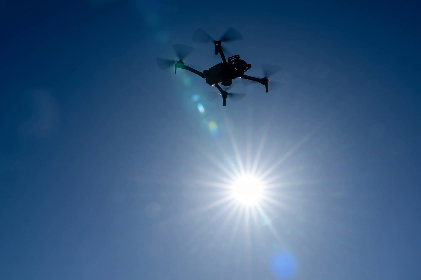 A drone flying against the sun
