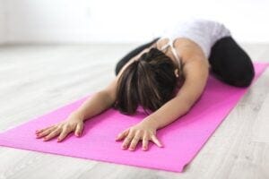Woman stretching on a pink yoga mat. Pixabay