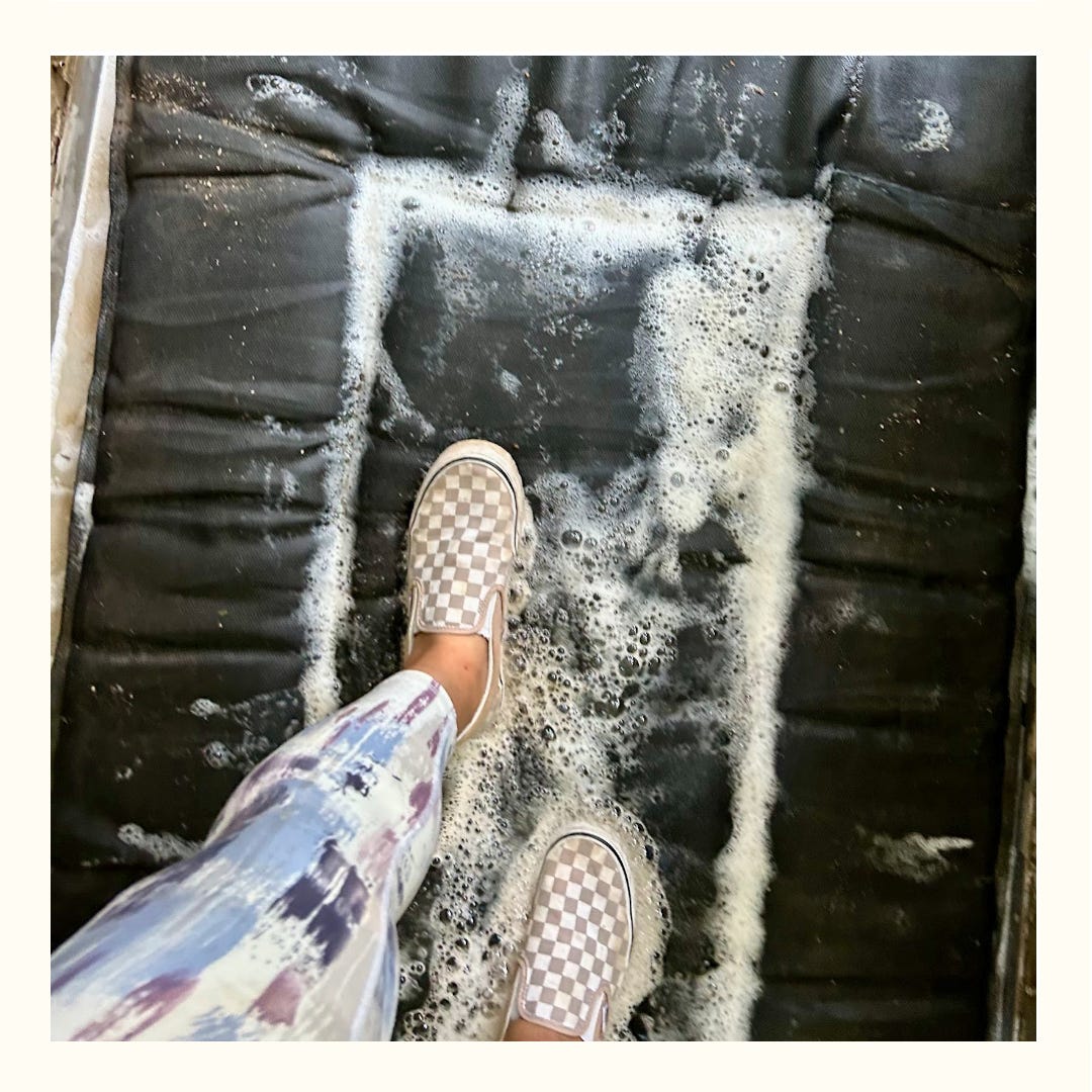 Nicole's pink Vans slip-ons step on a sudsy, black rectangular mat.