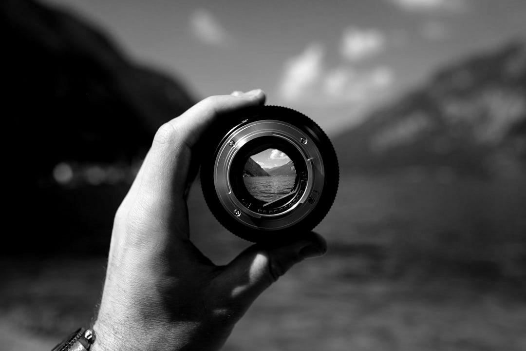 person holding camera lens person holding camera lens