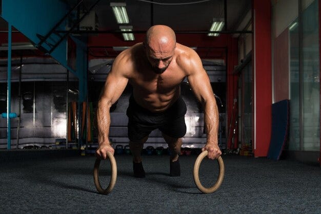 Sporty indian strong man doing push-ups on rings. | Premium Photo
