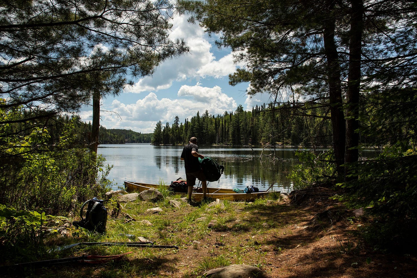 A man hoists a bag into a canoe. A man hoists a bag into a canoe.