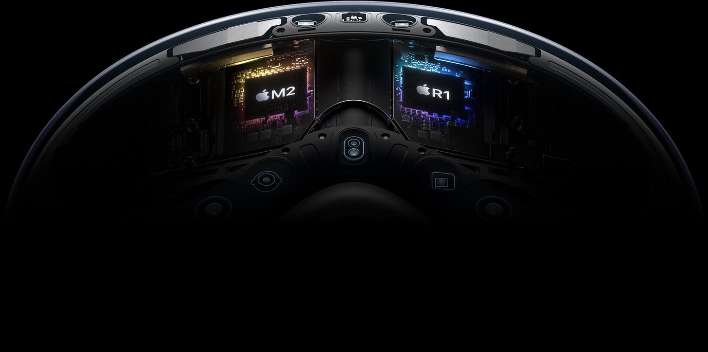 A unique dual‑chip design enables the spatial experiences on Apple Vision Pro. The powerful M2 chip simultaneously runs visionOS, executes advanced computer vision algorithms, and delivers stunning graphics, all with incredible efficiency. And the brand-new R1 chip is specifically dedicated to process input from the cameras, sensors, and microphones, streaming images to the displays within 12 milliseconds — for a virtually lag-free, real-time view of the world.