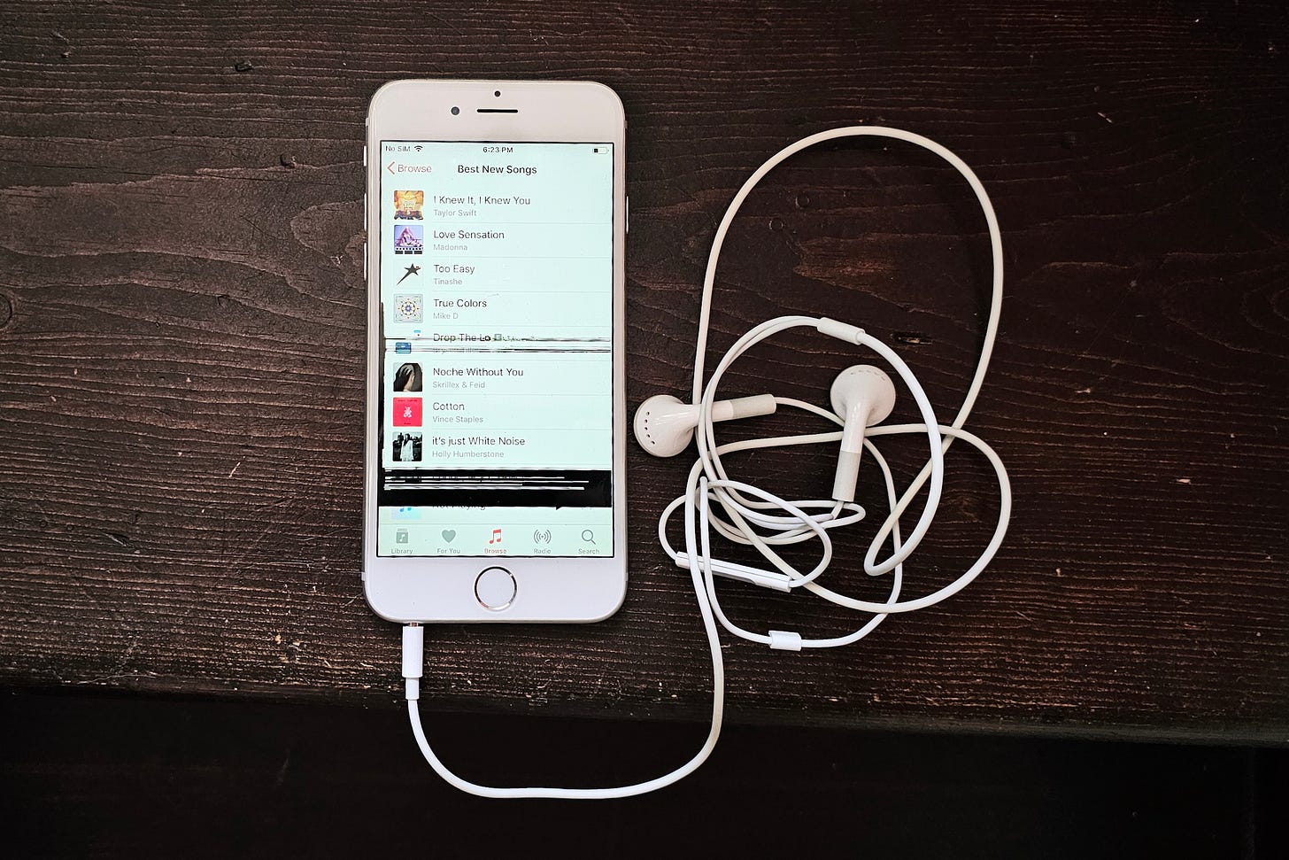 An iPhone 6 with Apple Music on the screen and a set of white Apple earbuds attached. An iPhone 6 with Apple Music on the screen and a set of white Apple earbuds attached.