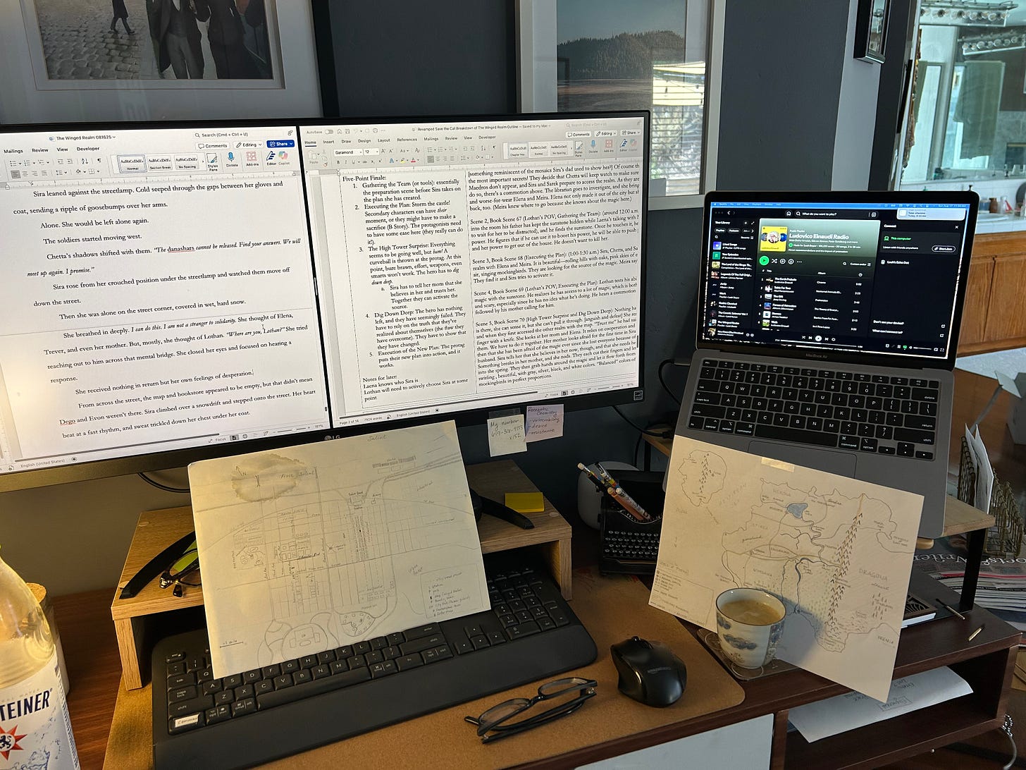 Desktop with a widescreen monitor, laptop, and notes.