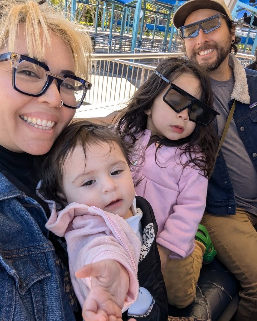 Chef Candice smiles at the camera, holding her two daughters and her husband smiles in the background.