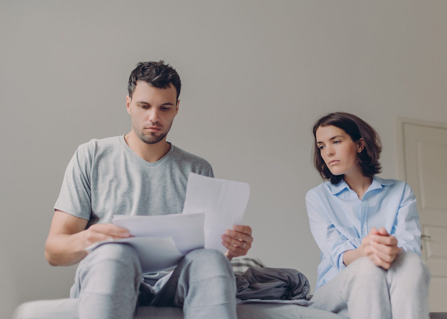 A man shuffles through a stack of papers while his partner looks on sadly.