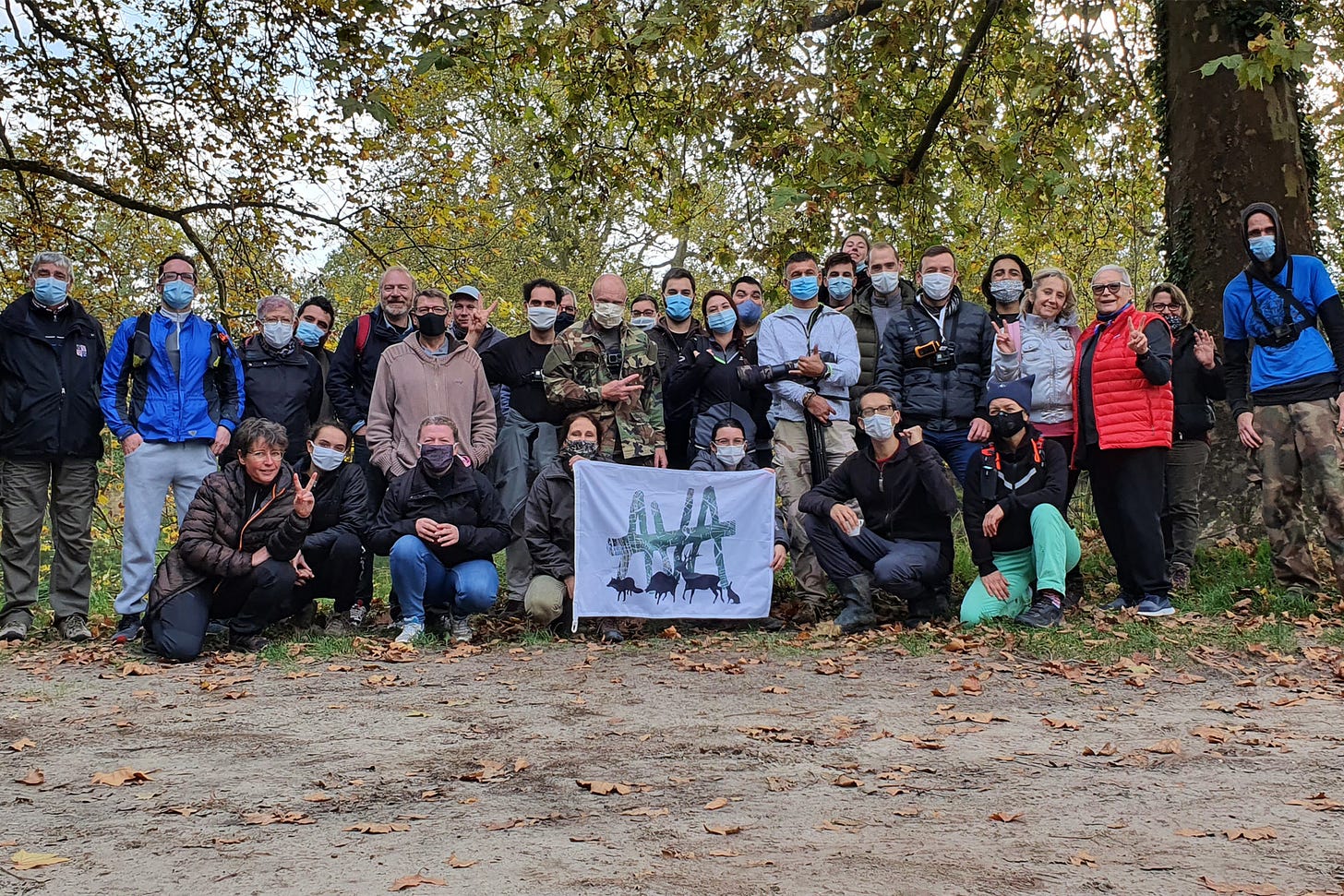 A group of about 25 people pose for a photo holding the AVA flag.