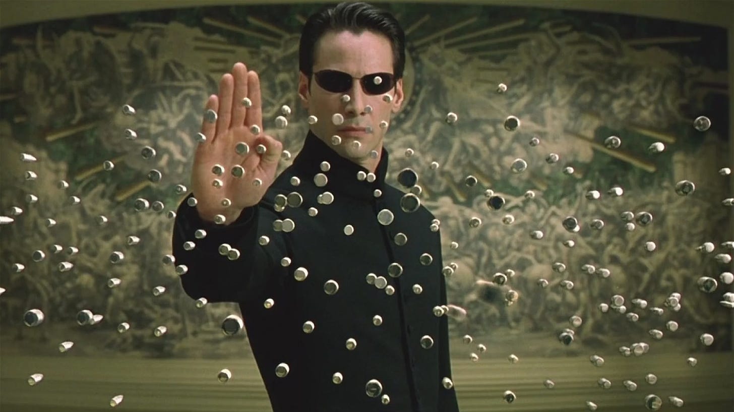 A person in black sunglasses holding up his hand

Description automatically generated