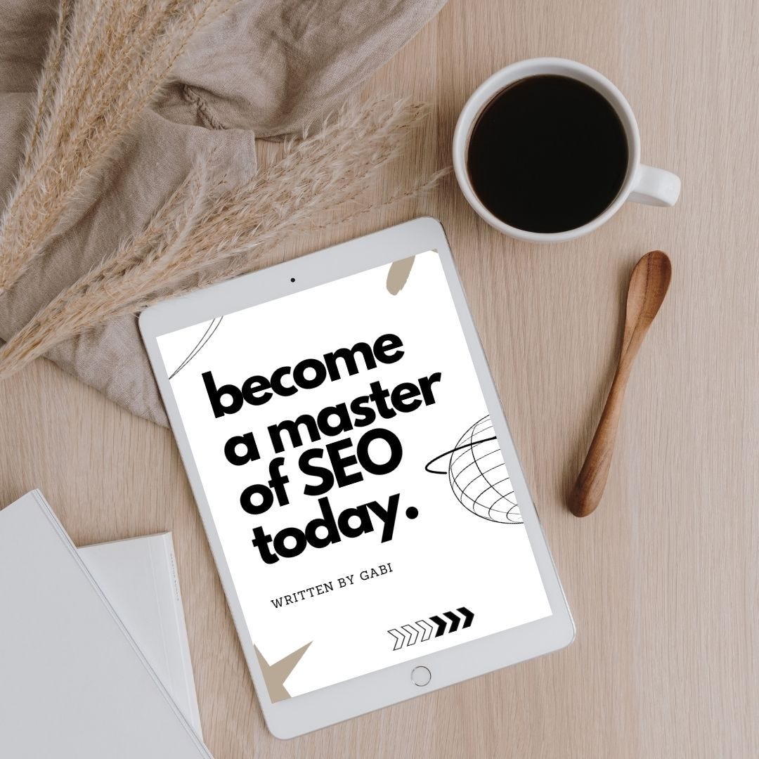 Brown desk with coffee, papers, spoon, tablet showing Gabi’s eBook "Become a Master of SEO Today" for content creators.