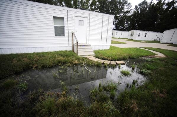 FILE - Fetid water stands outside a mobile home in a small mobile home park in rural Hayneville, Ala., Lowndes County, Aug. 1, 2022. The U.S. Department of Justice on Thursday, May 4, 2023, said an environmental justice probe found Alabama engaged in a pattern of inaction and neglect regarding the risks of raw sewage for residents in the impoverished Alabama county and announced a settlement agreement with the state. (AP Photo/Jay Reeves, File)