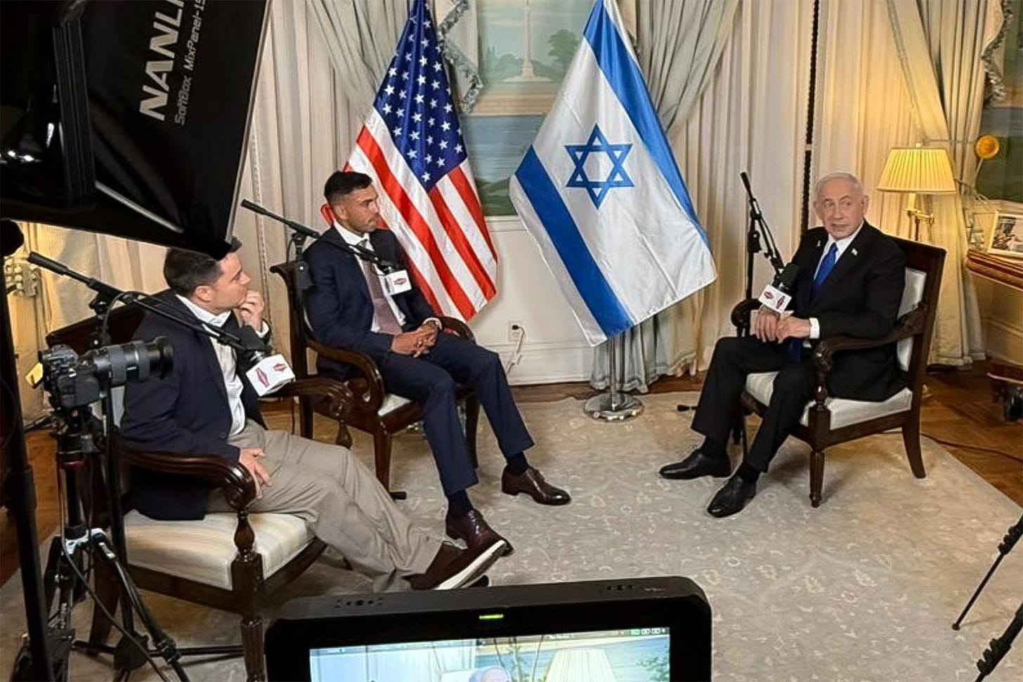 Israeli Prime Minister Benjamin Netanyahu sits for an interview with the Nelk Boys with a U.S. and an Israeli flag in the background.