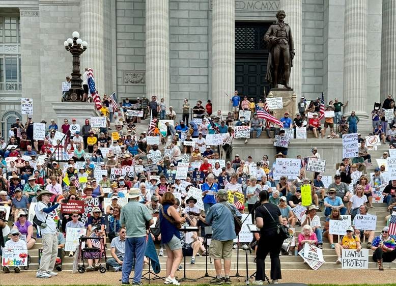 A group of people sitting on steps with signs

AI-generated content may be incorrect.
