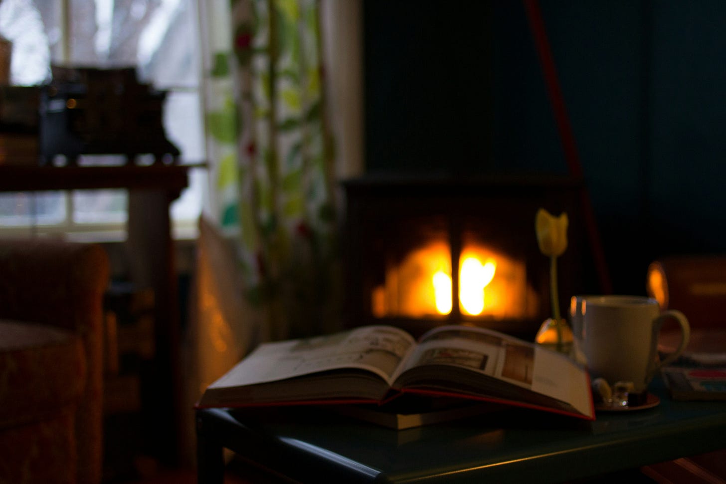 Image of a cozy den with a fire and a coffee cup.