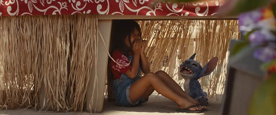 A little girl (Lilo) and her blue alien pet hide under a table laughing. A little girl (Lilo) and her blue alien pet hide under a table laughing.