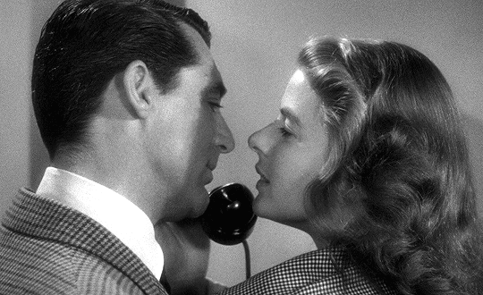 This may contain: a man and woman are talking on the telephone while holding each other's heads