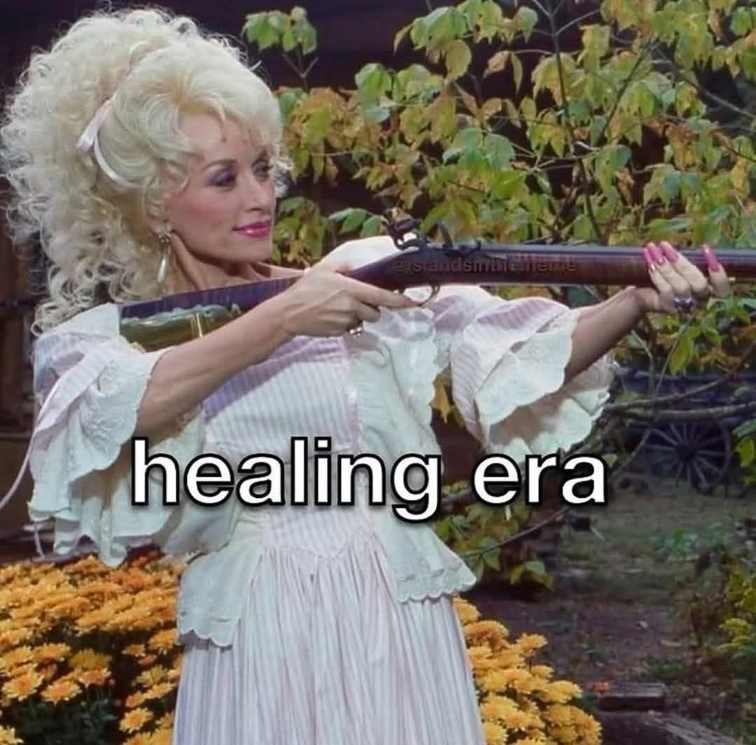 Dolly parton holding a gun that says healing era
