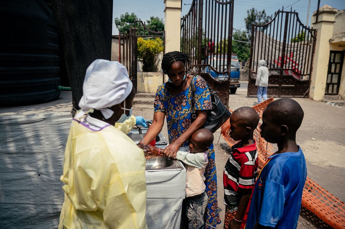 A mother helps her children wash their hands before entering Kyeshero Hospital at A mother helps her children wash their hands before entering Kyeshero Hospital at