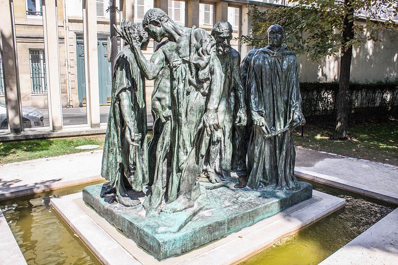 The Burghers of Calais: six bronze figures in long robes with ropes around their necks, standing in the garden of the Musée Rodin