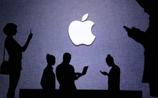 Silhouettes of people using technology in front of Apple logo