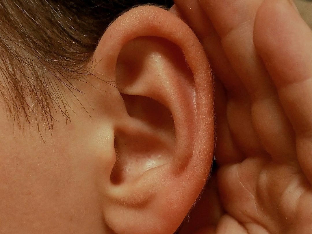A person cupping their ear to listen closely
