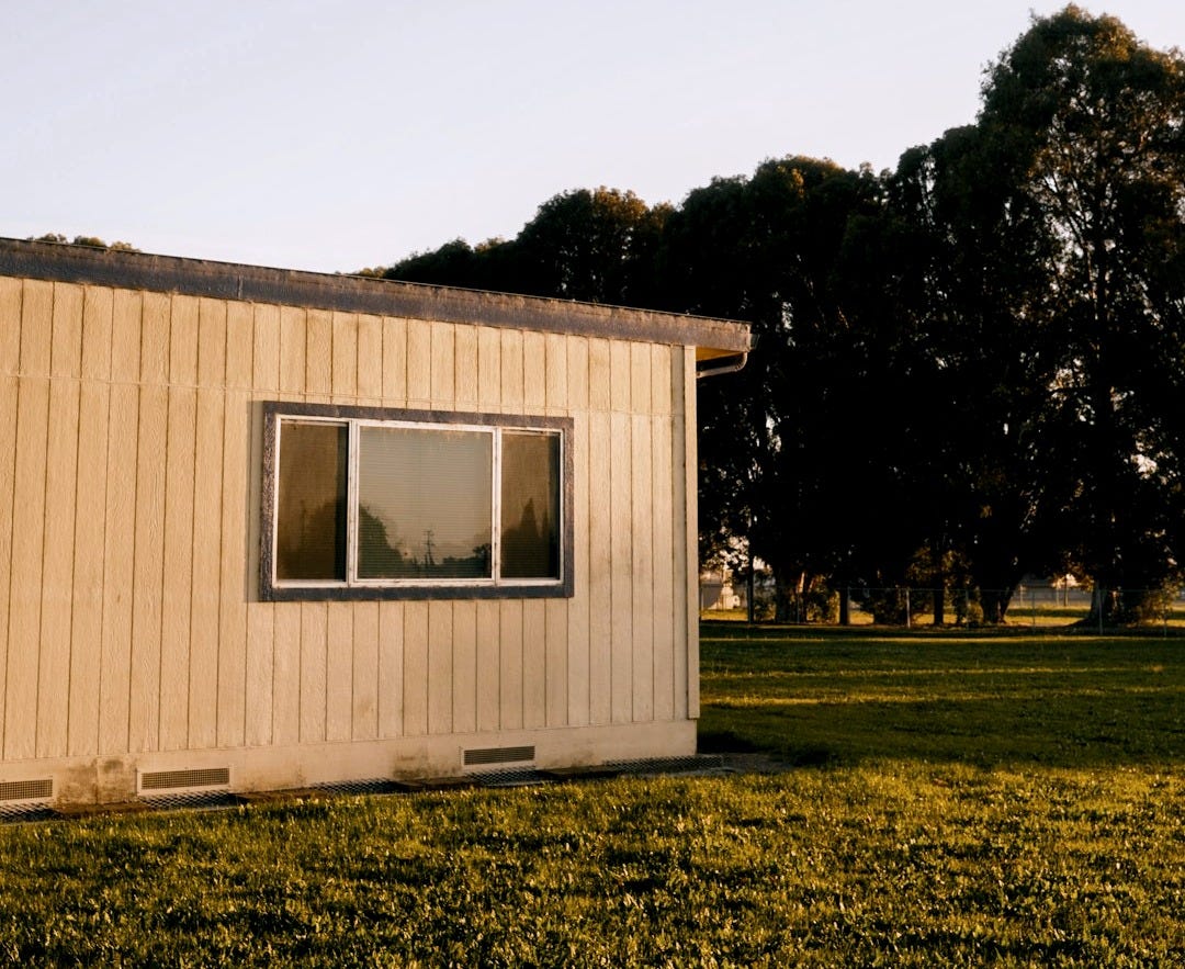 white and brown wooden house near green trees during daytime