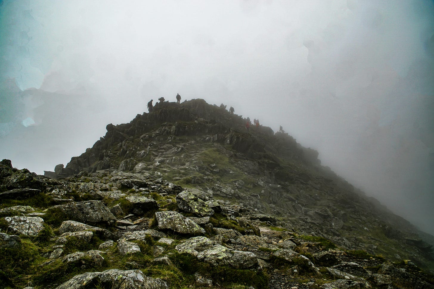Figures on a rocky peak in fog