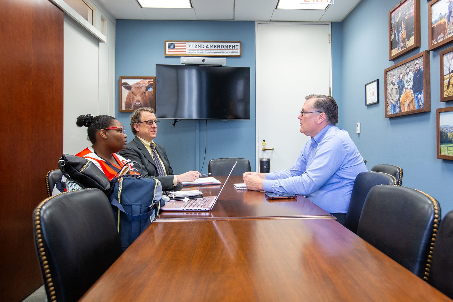 three people seated at a table in a Congressional office three people seated at a table in a Congressional office