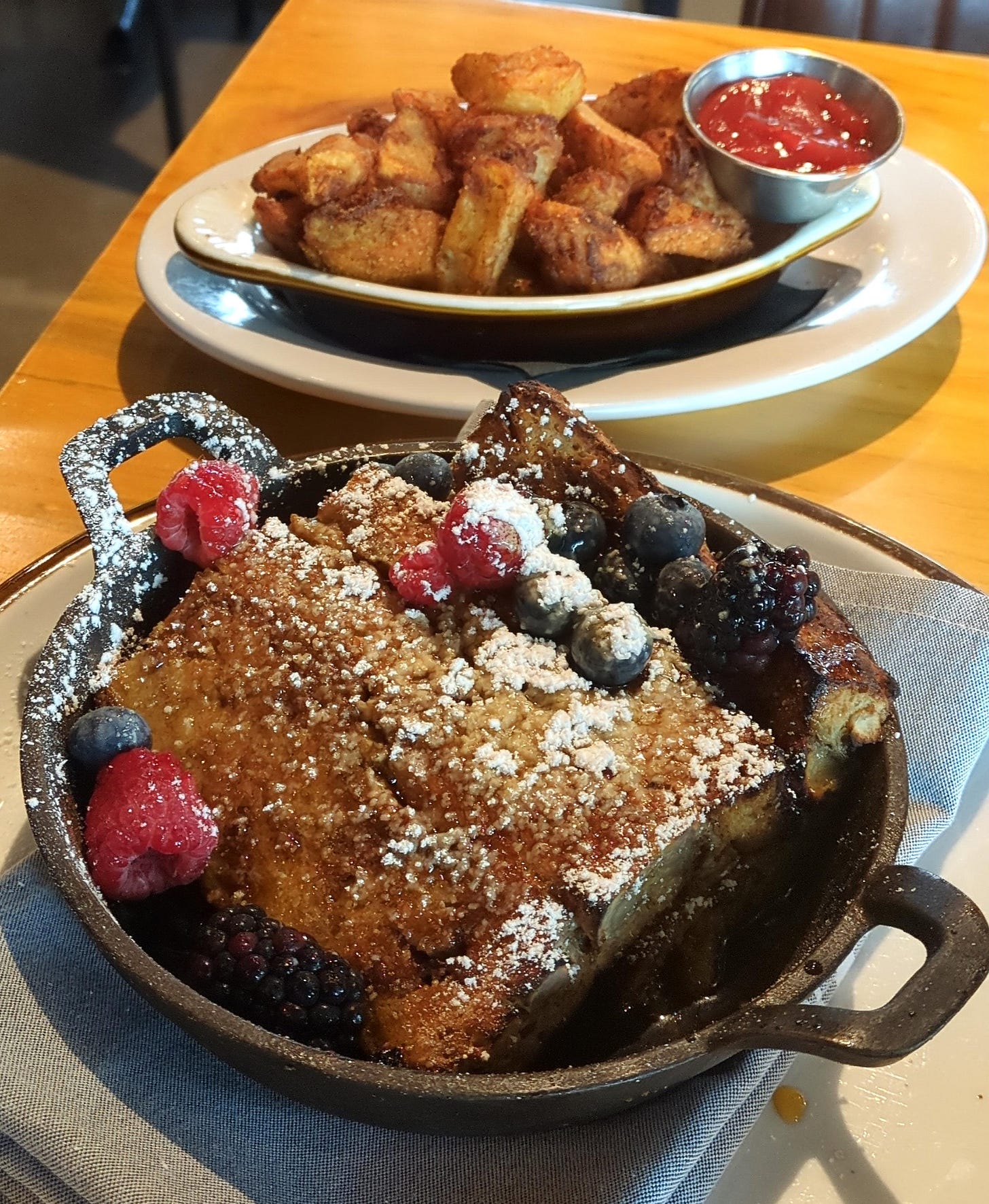 Breakfast potatoes and a searing hot cast iron skillet of banana French toast casserole
