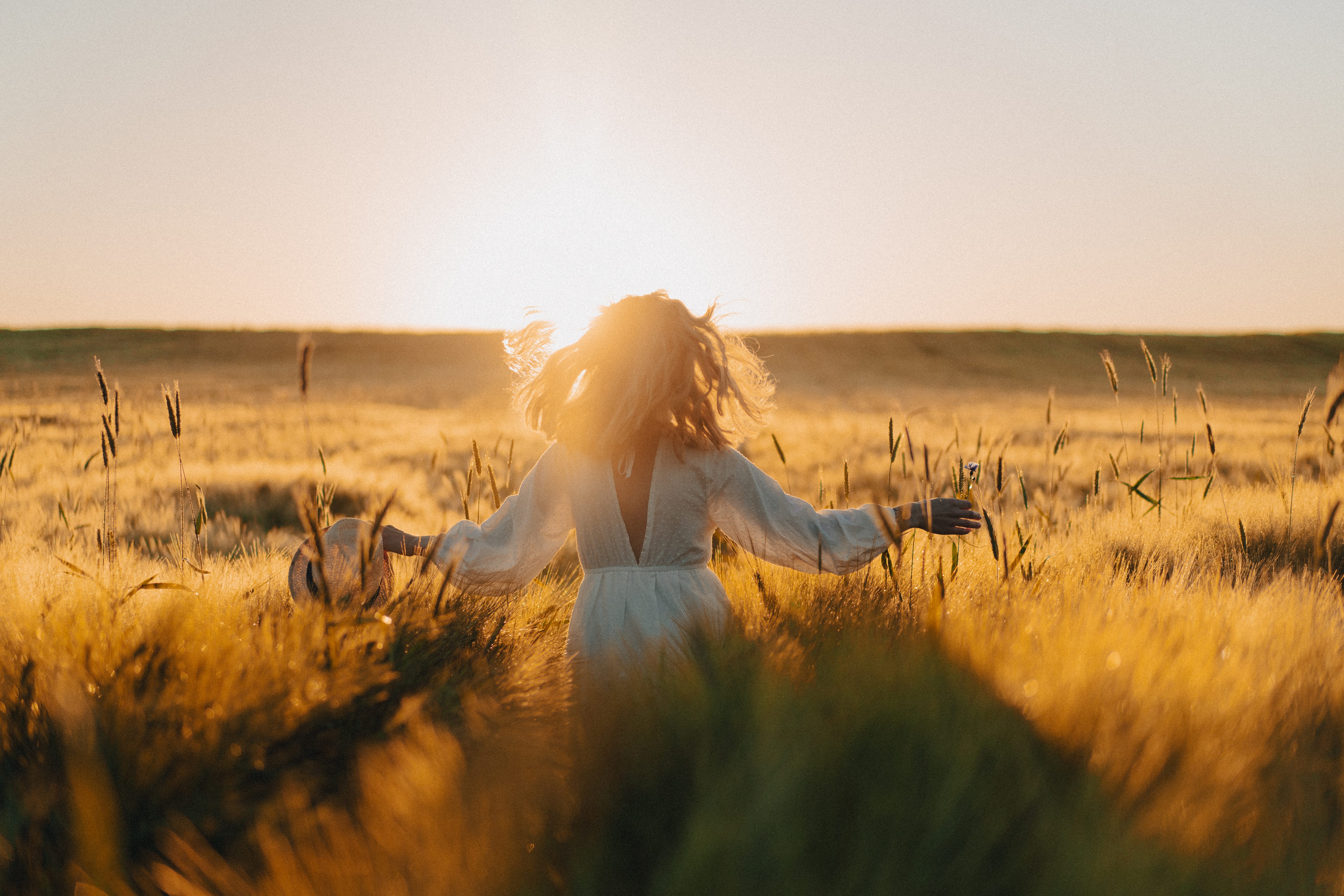 Woman facing the sun in a field of wheat.