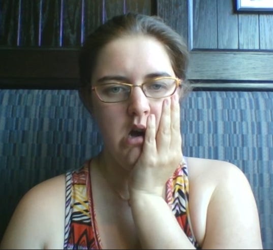 Jerrica stares with her mouth agape and her hand to her cheek.