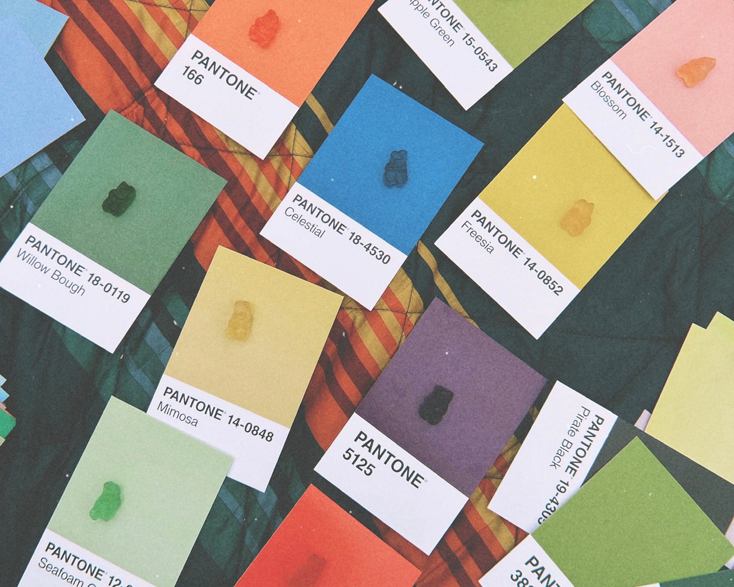 Gummy bears sitting on top of their corresponding Pantone color postcards