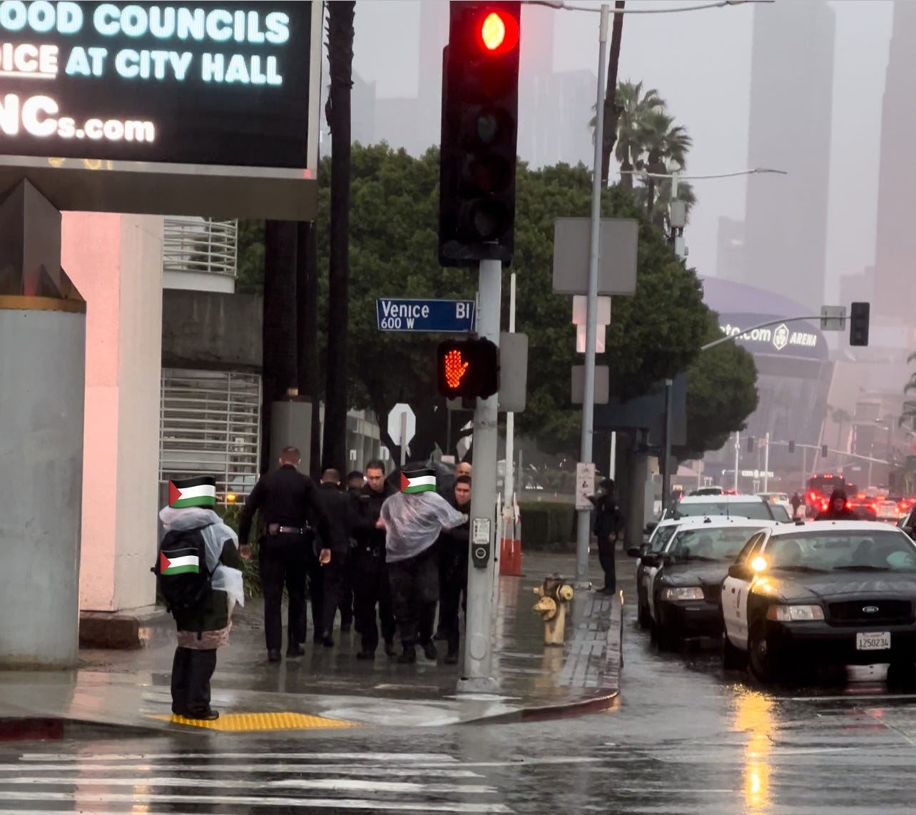 On the intersection a sign reads Venice. Police officers escort a demonstrator as another waits for their release.