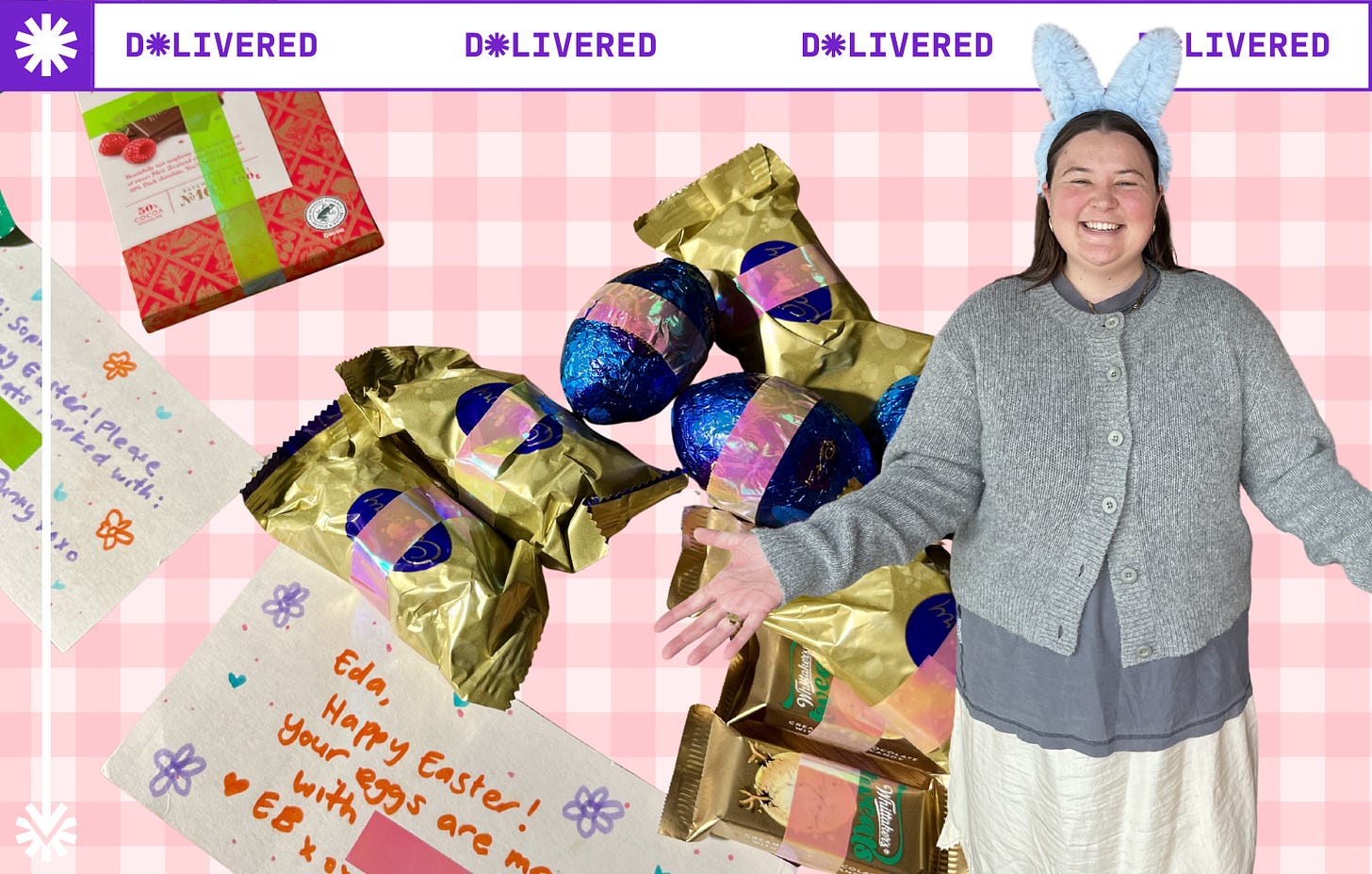 On a pink gingham background there are easter chocolates with pink tape over them. In the foreground, Geo Cocks is grinning at the camera wearing bunny ears