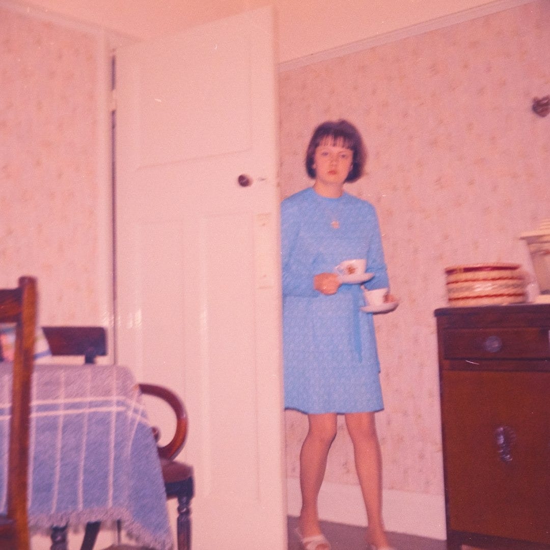 Woman in blue dress holding teacups in room