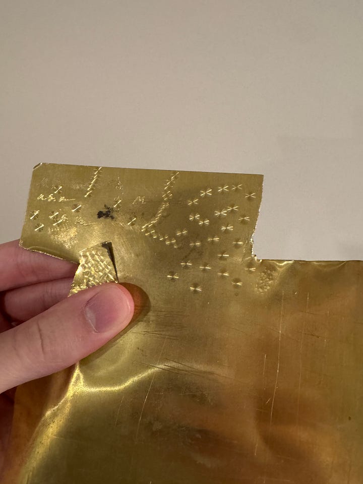 A photograph of amateur perlage work on brass sheet metal, as performed with a simple drill press and Cratex setup.
