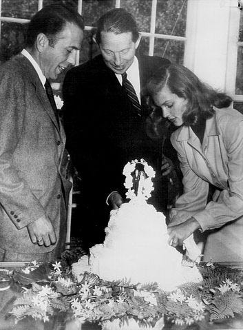 Humphrey Bogart, Louis Bromfield, and Lauren Bacall around wedding cake Humphrey Bogart, Louis Bromfield, and Lauren Bacall around wedding cake