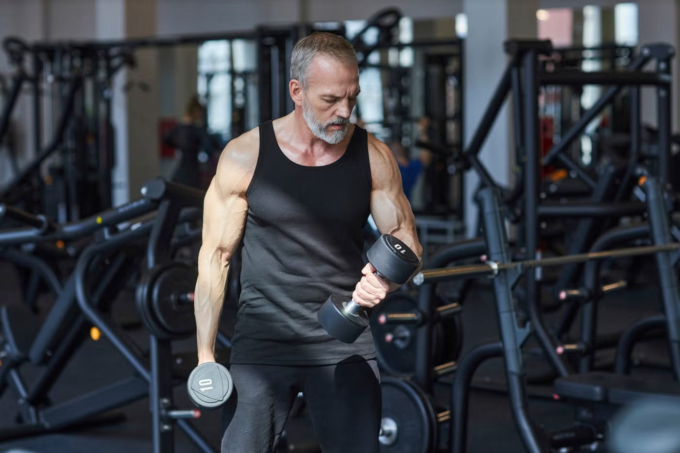 Strong, older man doing dumbbell curls in the gym. Strong, older man doing dumbbell curls in the gym.