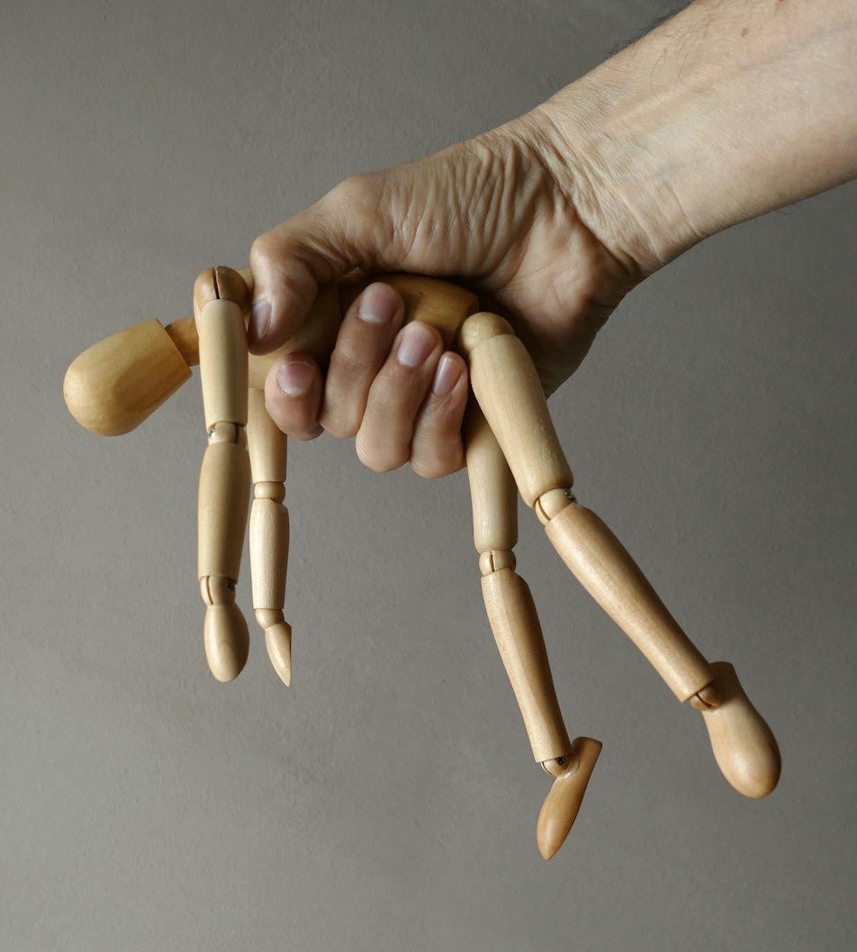 person holding brown wooden mannequin