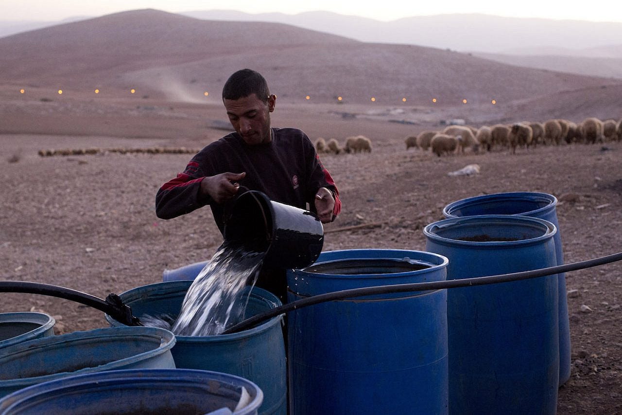 A Palestinian farmer fills water tanks in the West Bank village of Khirbet al-Makhoul, Jordan Valley, October 9, 2013. (Activestills.org) A Palestinian farmer fills water tanks in the West Bank village of Khirbet al-Makhoul, Jordan Valley, October 9, 2013. (Activestills.org)