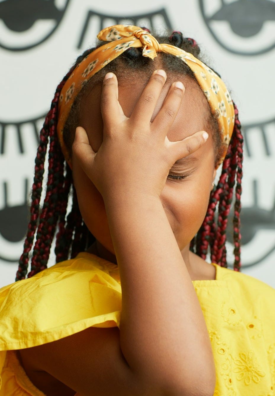 A little girl covering her face with her hands