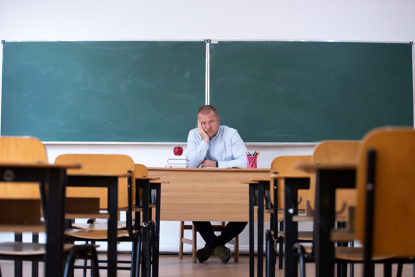 Sad teacher in empty classroom