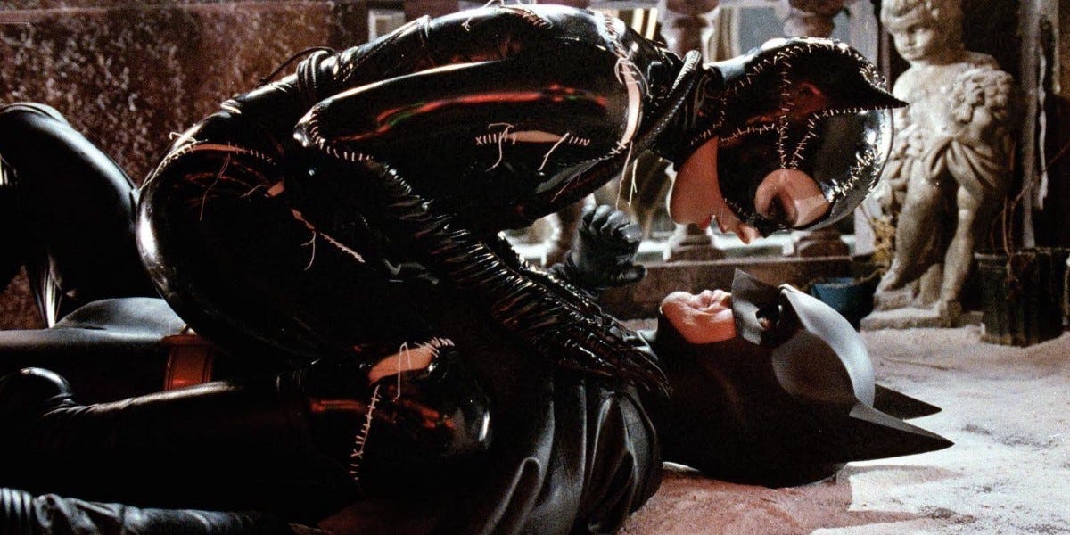 Movie still from Batman Returns: Catwoman sits on top of Batman